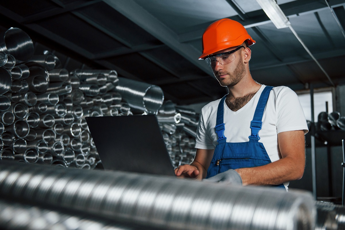 Production of metal pipes. Man in uniform works on the production. Industrial modern technology