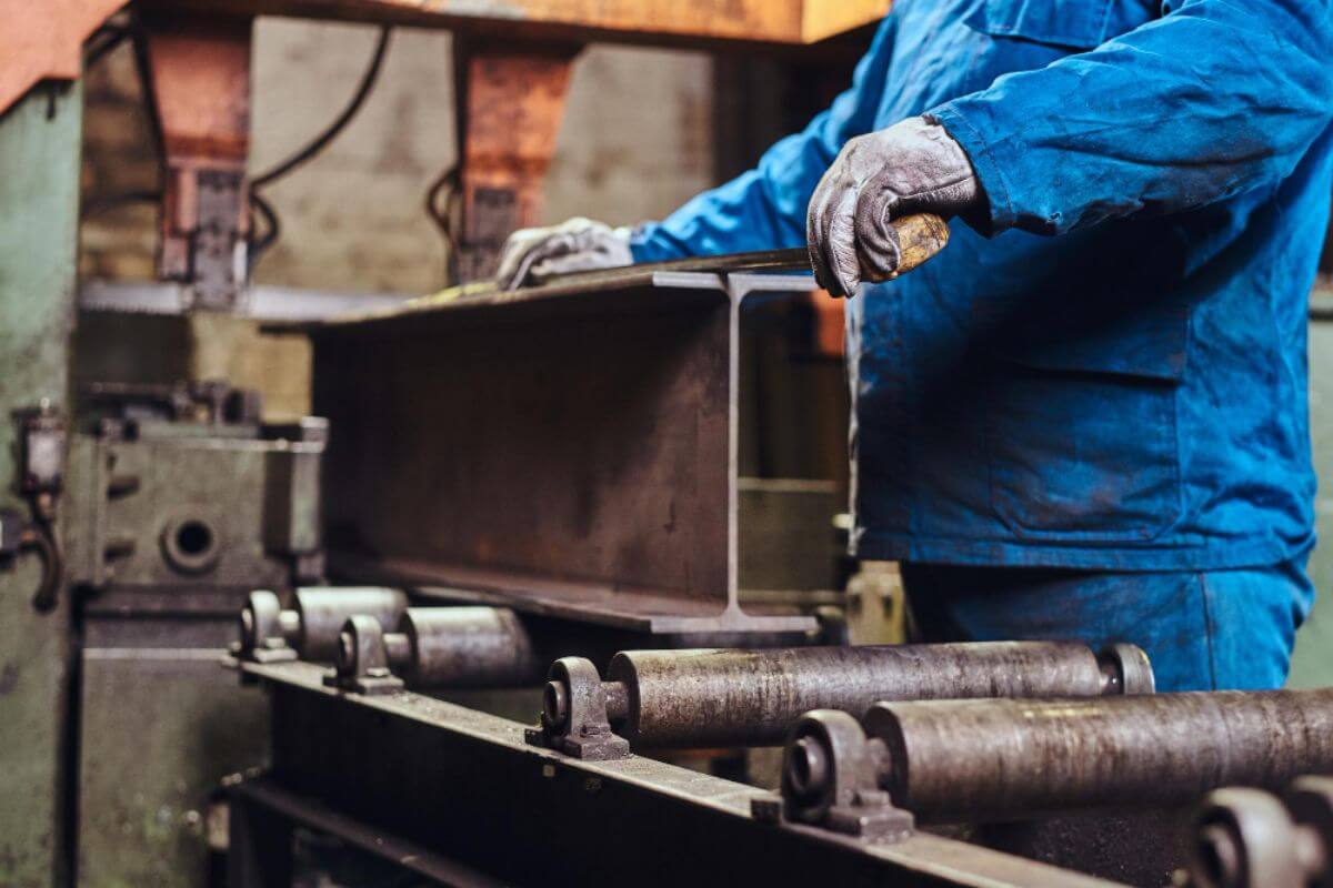 Steel fabricator measuring a newly made I-beam, ensuring accuracy and quality in structural steel production.