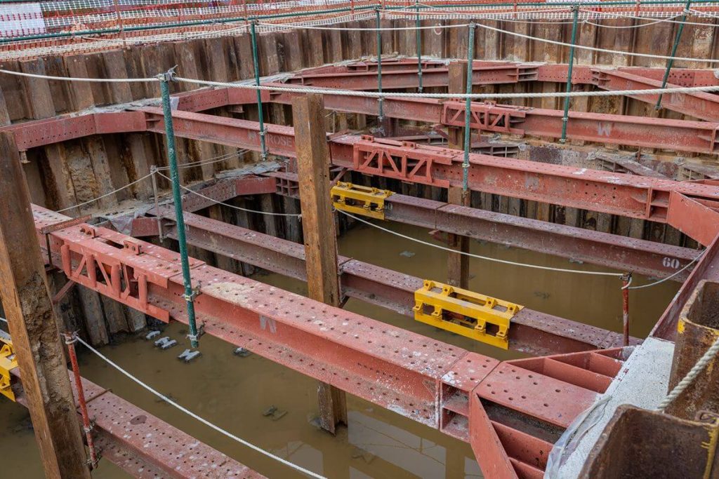 Structural steel framing and sheet piles at a construction site exposed to water and severe weather conditions