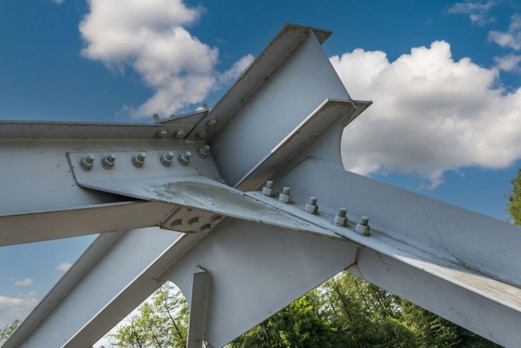 Close-up of structural H beam connections with bolted steel plates against a blue sky